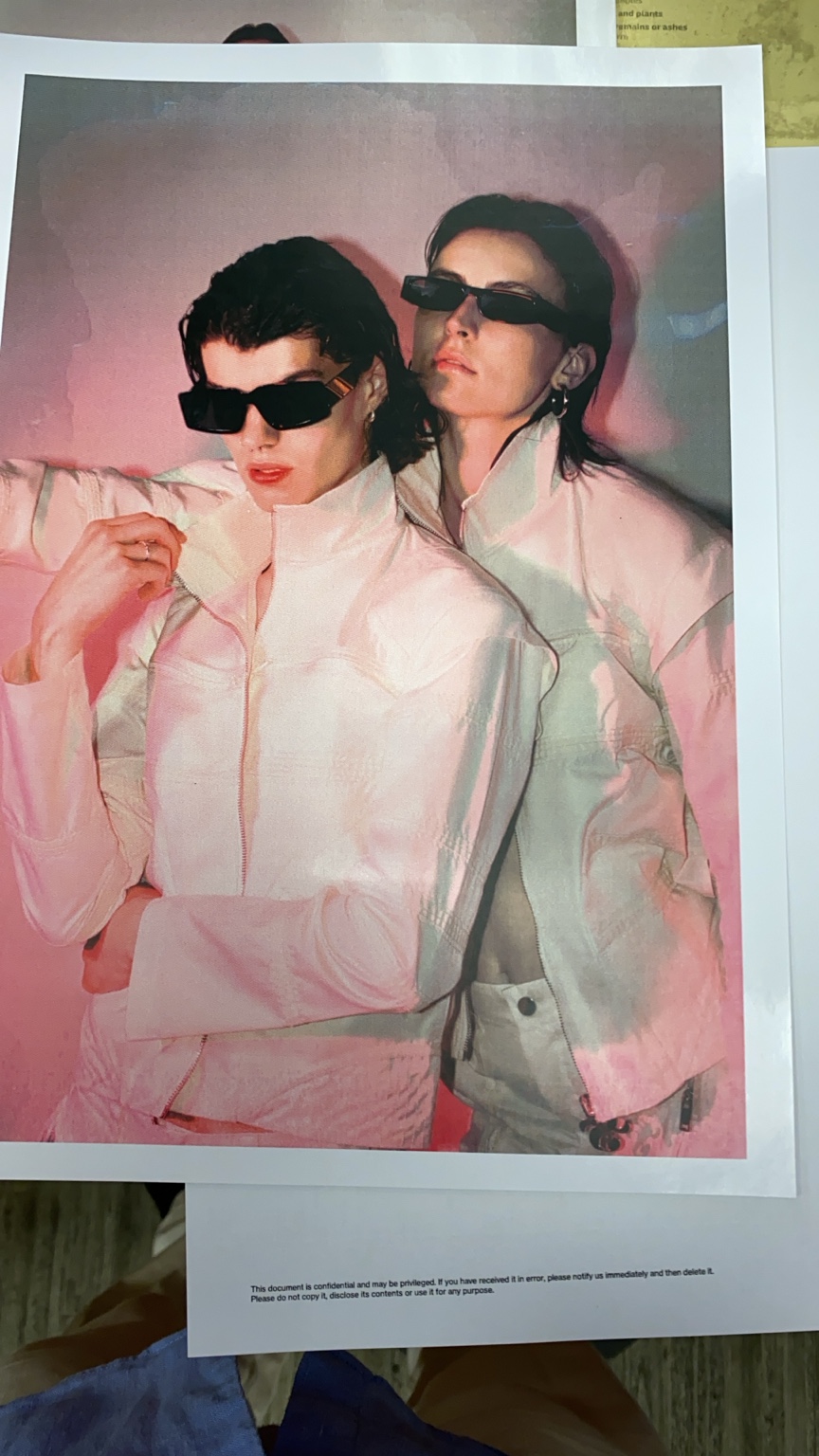 Printed campaign portrait of two models in white jackets and black sunglasses
