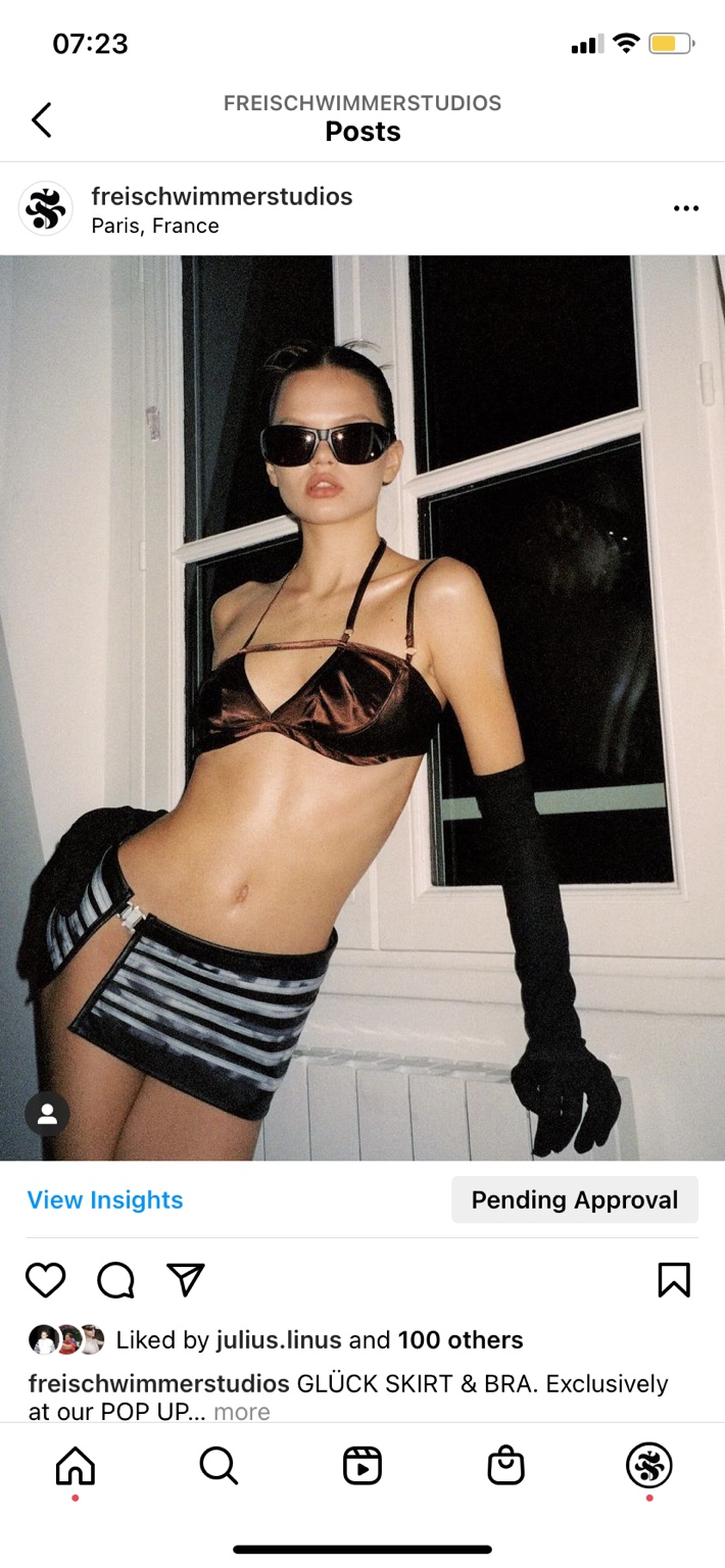 Campaign look with sunglasses, satin bra, striped skirt and long black gloves